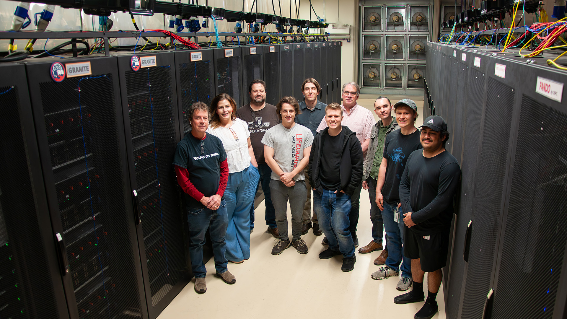 People pose between rows of computer servers